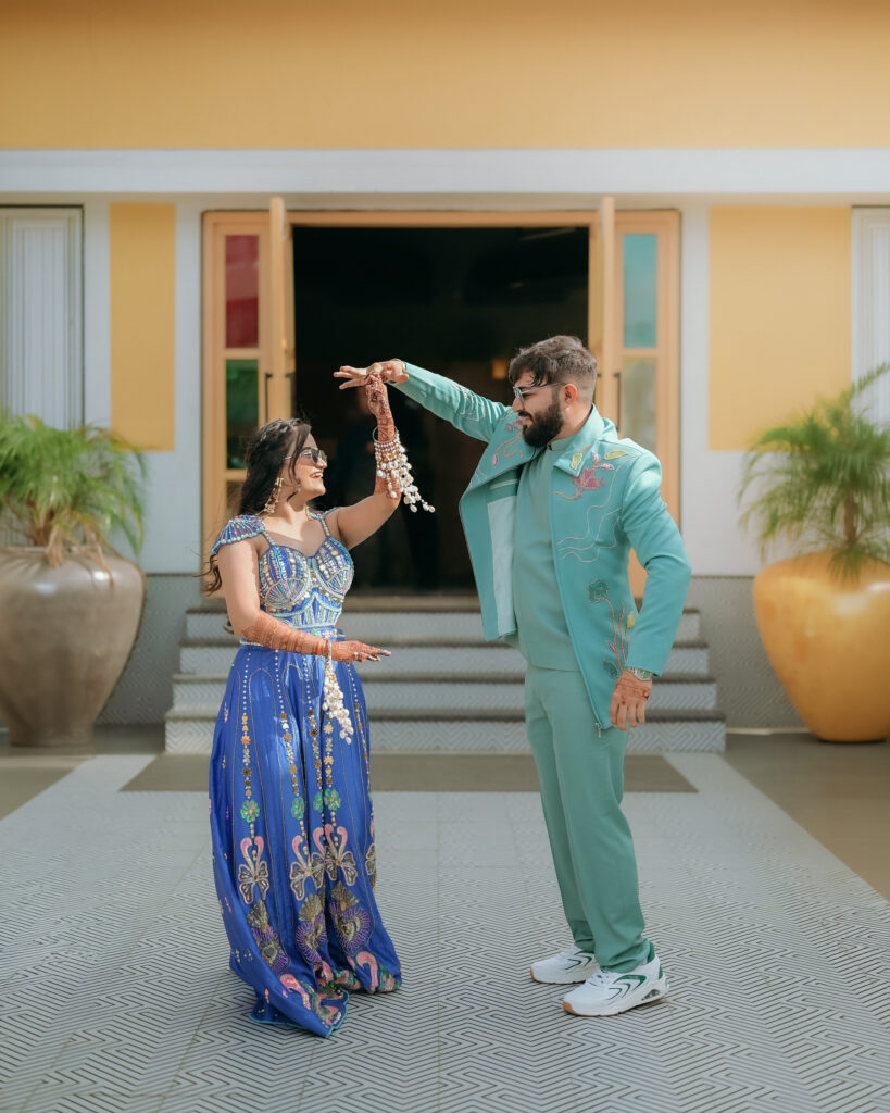 Groom twirling the bride in a playful dance step outside the entrance, candid wedding photography in Solapur