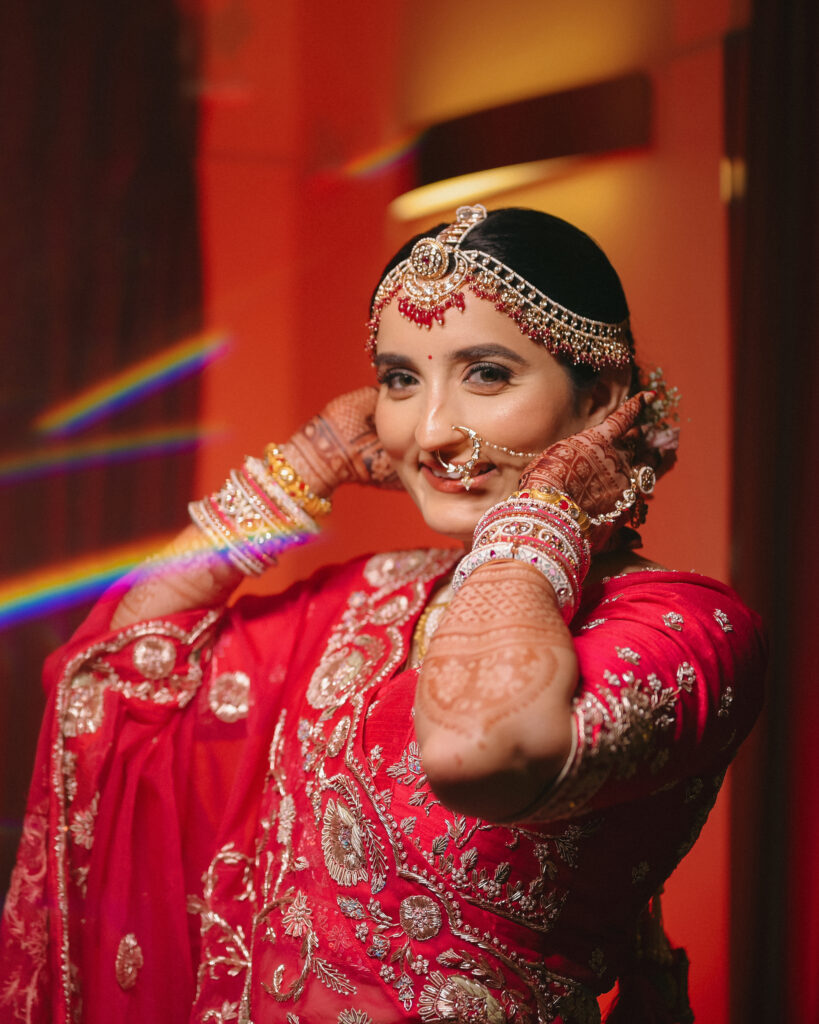 Smiling bride in red lehenga with chooda bangles and mehendi hands, bridal portrait photography in Lonavala